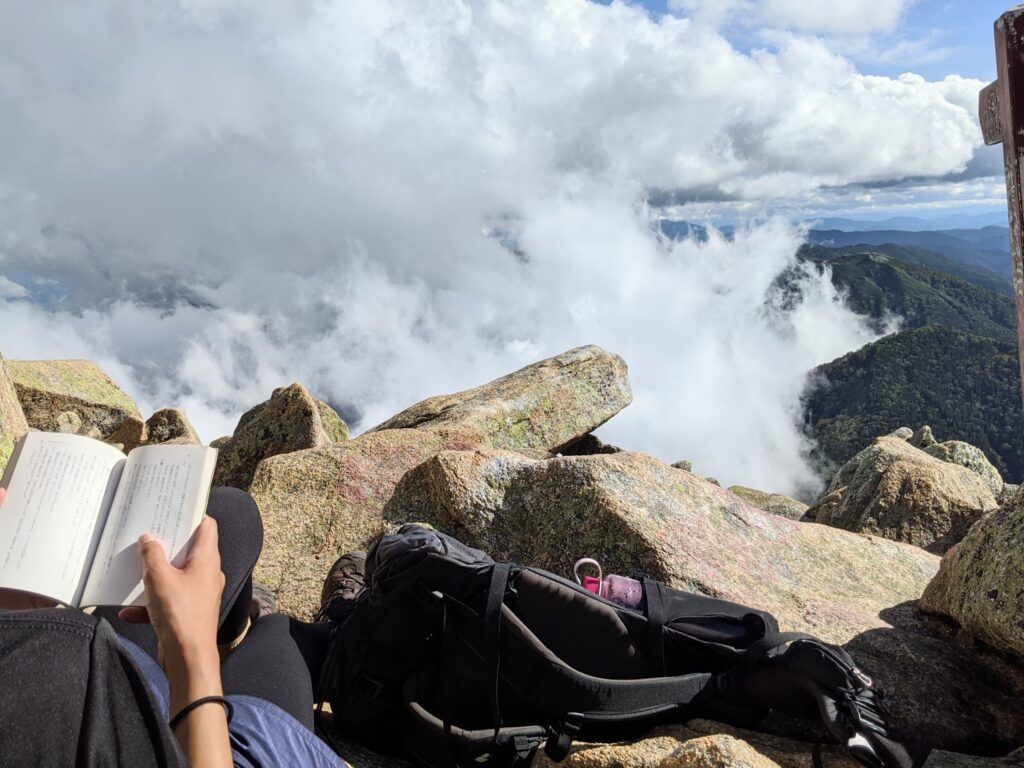 山頂で読書をする筆者